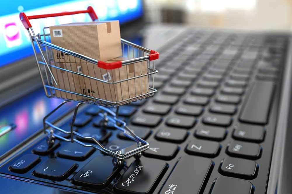Einkaufswagen mit Paketen auf Tastatur für Online-Shopping.