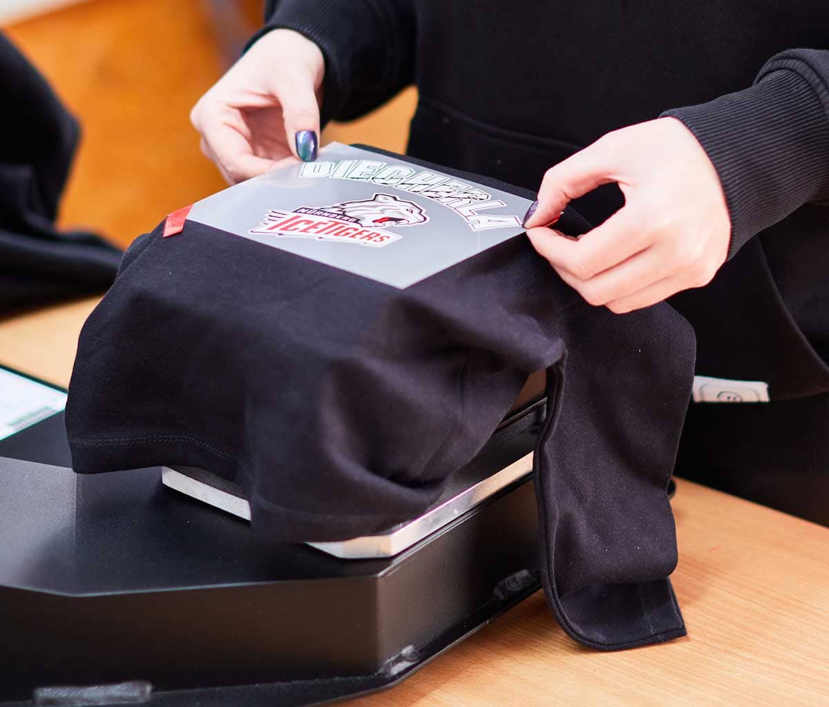 Transferdruck auf schwarzem Textil mit Druckmaschine bei Orange Key.