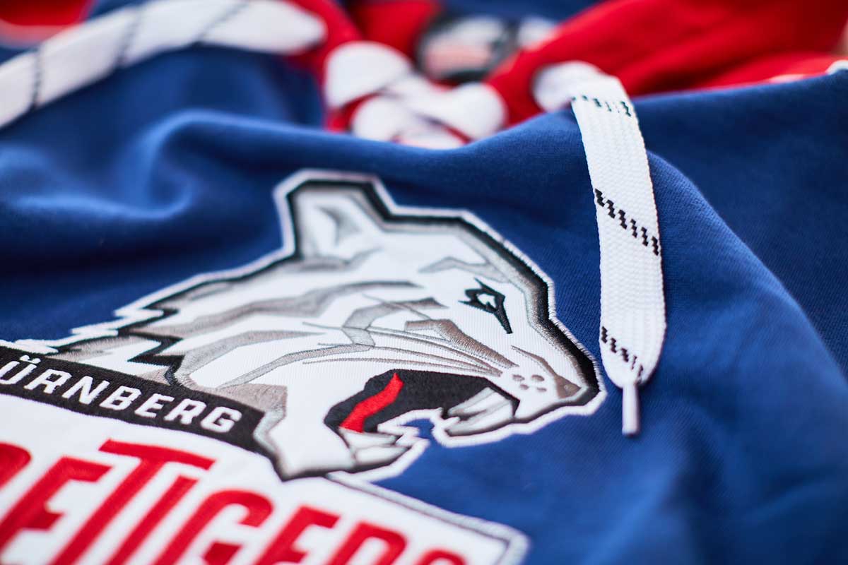 Eishockey Logo mit Wolf und Schriftzug auf blauer Jacke.