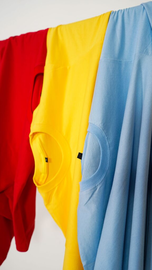 Bunte T-Shirts in Rot, Gelb und Blau zum Versand bereit.